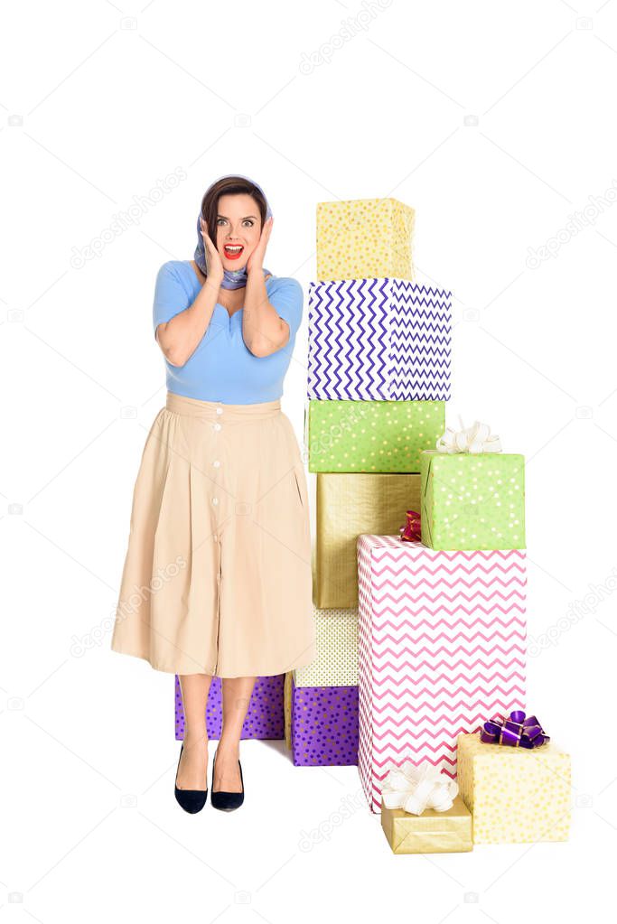 surprised stylish woman standing near gift boxes and looking at camera isolated on white