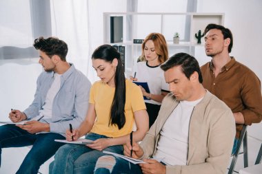 İşadamları ve iş kadınları casual giyim içinde defter ofiste iş eğitim notları yapım odaklı