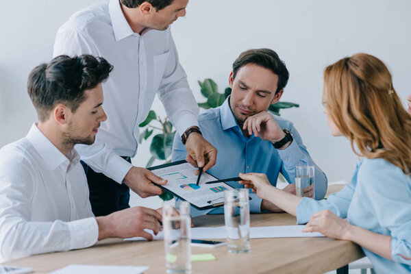группа бизнесменов, работающих над бизнес-планом на рабочем месте в офисе
