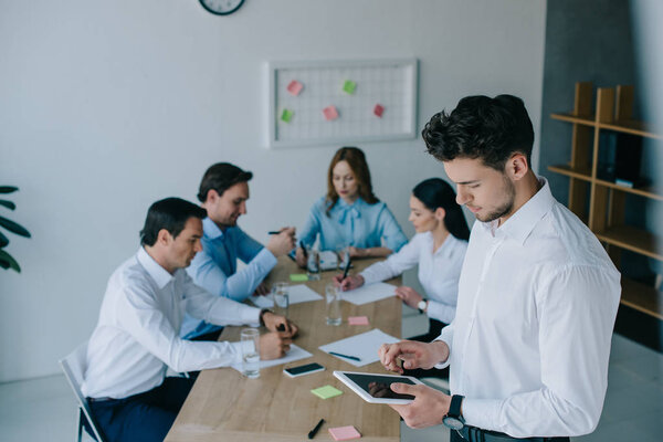 избирательная направленность бизнесмена с планшетом и сотрудниками на рабочем месте в офисе
