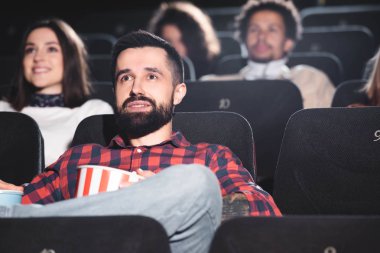 Patlamış mısır tutan ve sinemada film izleyen yakışıklı bir adamın seçici odak noktası. 