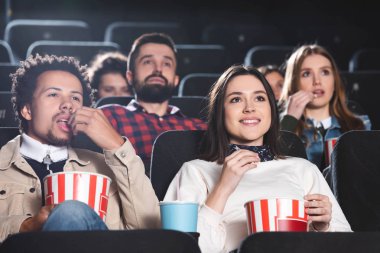 Patlamış mısır yiyen ve sinemada film izleyen çok ırklı arkadaşların seçici odağı 
