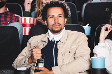 Seçici odak noktası, dijital kamerayla çekim yapan ve sinemada film izleyen Afrikalı Amerikalı bir adam. 