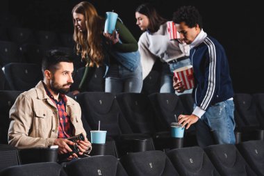 Dijital kamerayla çekim yapan ve sinemada film izleyen bir adamın seçici odağı