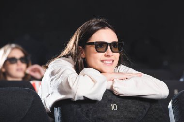 Üç boyutlu gözlüklü gülümseyen kadının sinemada film izlediği seçici odak noktası. 