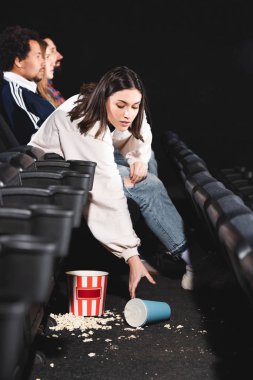 Çekici bir kadın sinemada yerden soda ile kağıt bardak alıyor. 