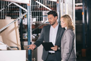 İş kadınının yanında dururken inşaat malzemelerini işaret eden yakışıklı iş adamı.