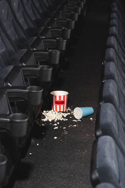 selective focus of popcorn and paper cup with soda on floor in cinema 