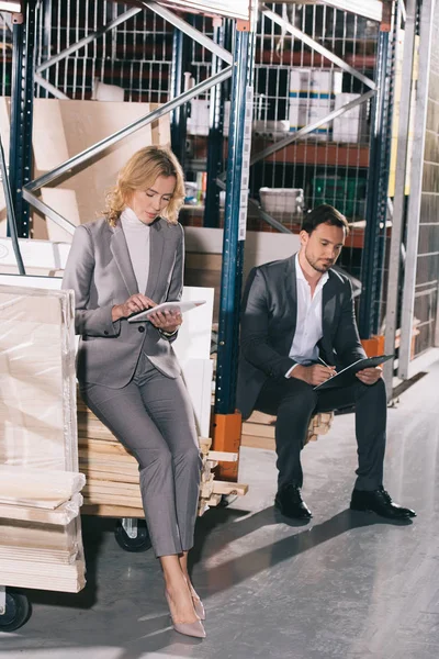 İşkadını, panoya yazı yazan işadamının yanında dijital tablet kullanıyor.