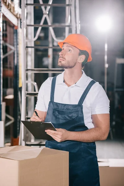 Concentrated Warehouse Worker Looking Away While Writing Clipboard — Stock Photo, Image