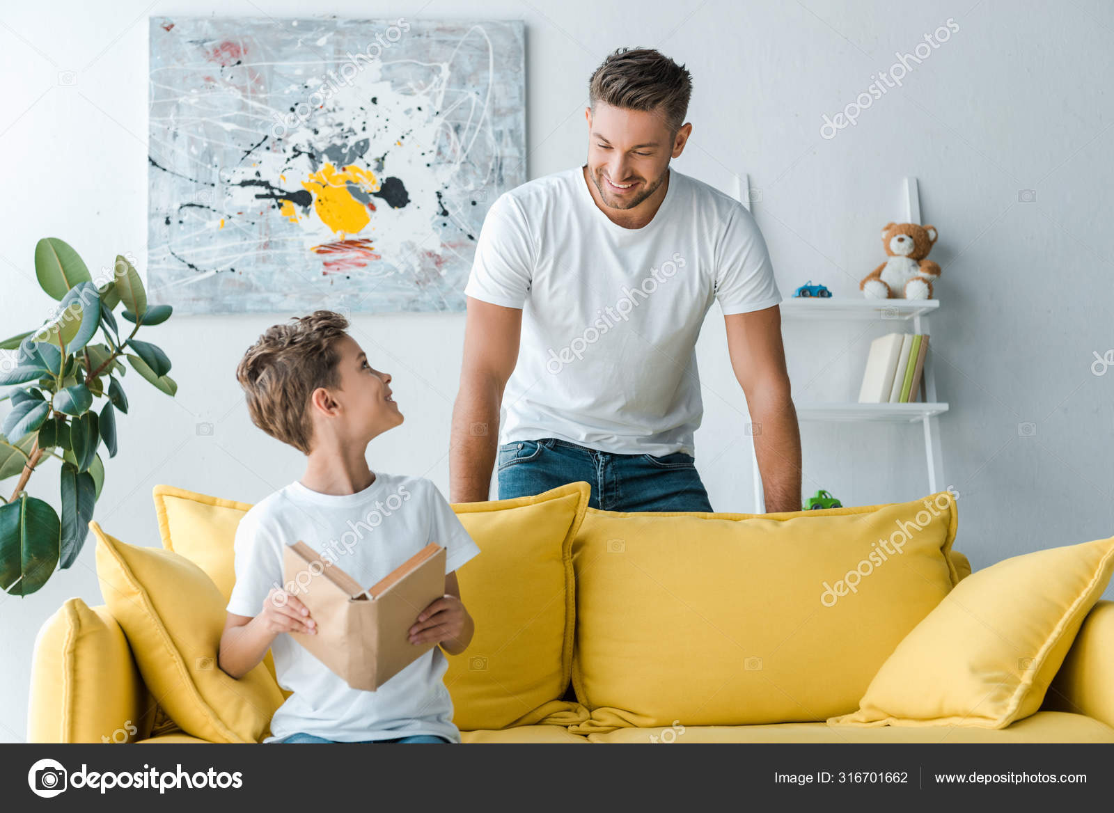 Glücklicher Vater Neben Sohn Mit Buch Auf Sofa Sitzend — Stockfoto