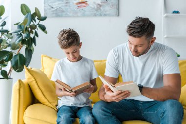Yakışıklı baba ve oğul evde kitap okuyor. 