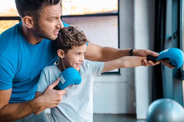 Baba, boks eldivenli yakışıklı oğlunun ellerine dokunuyor. Spor salonunda egzersiz yapıyor. 
