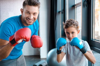 Mutlu baba ve yakışıklı oğul boks eldivenleriyle spor salonunda çalışıyor. 