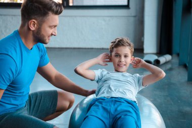 Neşeli baba neredeyse mutlu çocuk fitness topu üzerinde çalışıyor. 