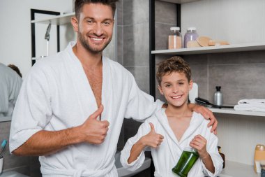 happy father and cheerful son showing thumbs up in bathroom  clipart