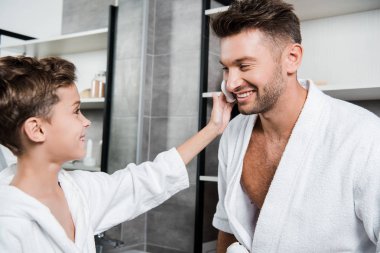 Çocuğun yüzüne tıraş köpüğü süren mutlu bir çocuğun seçici odak noktası. 