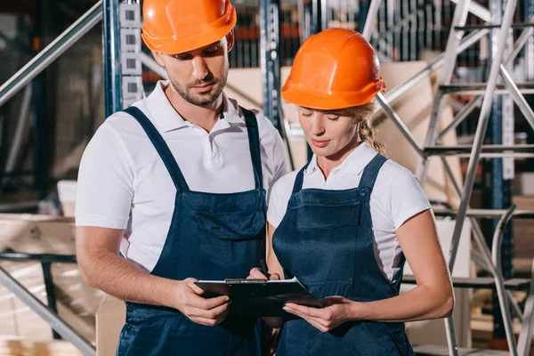 Concentrated Warehouse Workers Looking Clipboard Together — Stock Photo, Image