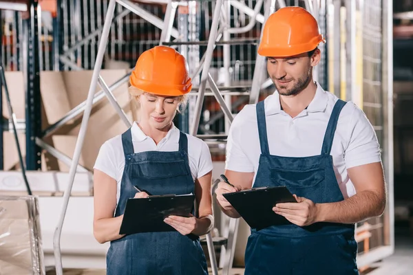 Positive Warehouse Workers Overalls Helmets Writing Clipboards — Stock Photo, Image