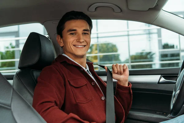 Uśmiechnięty Przystojny Mężczyzna Trzymający Pasy Bezpieczeństwa Samochodzie — Zdjęcie stockowe