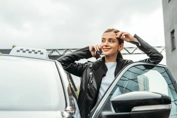 Uśmiechnięta Kobieta Taksówkarz Rozmawia Smartfonie Obok Samochodu — Zdjęcie stockowe
