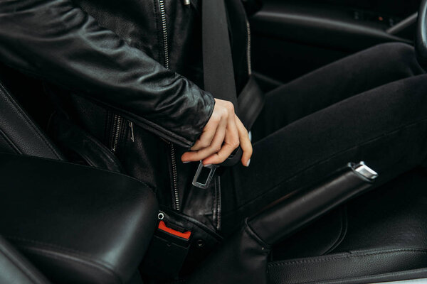 Cropped view of woman fasting safety belt in car