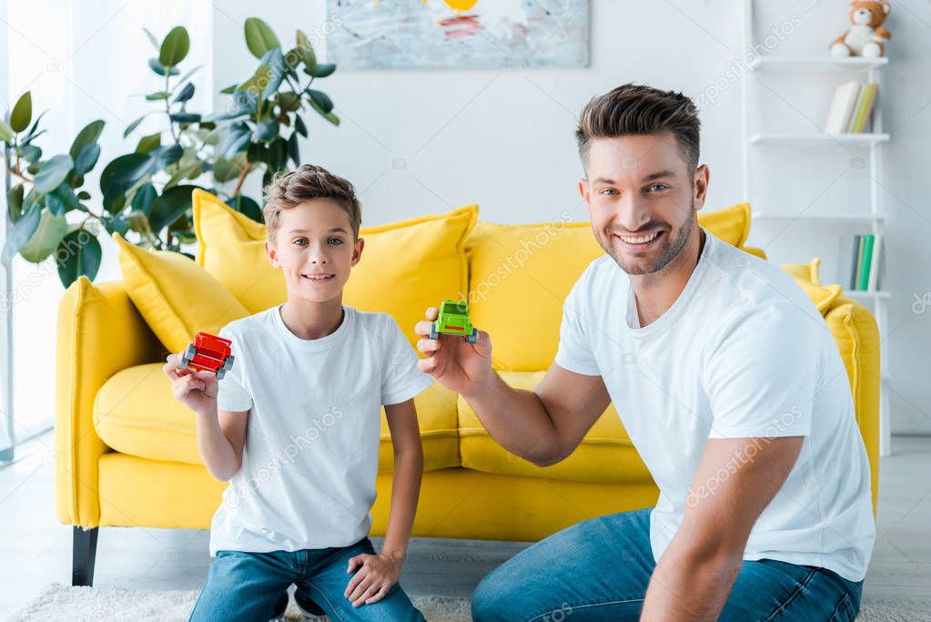 happy son and handsome father playing with toy cars at home 