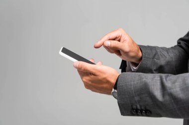 Takım elbiseli işadamının gri renkte izole edilmiş akıllı telefonu işaret etmesi. 