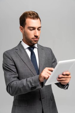 Takım elbiseli yakışıklı işadamı gri tablet kullanıyor. 