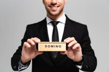 Takım elbiseli güler yüzlü iş adamının elinde tahta bir kutu ve gri harfli domino taşı vardı. 