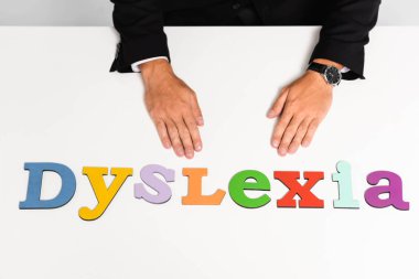 cropped view of businessman in suit sitting near dyslexia lettering  clipart