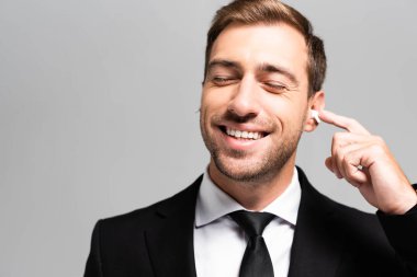 Takım elbiseli yakışıklı ve güler yüzlü iş adamı Grey 'de izole edilmiş müziği dinliyor. 