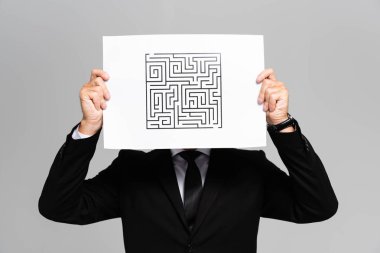 businessman obscuring face with paper with labyrinth isolated on grey  clipart