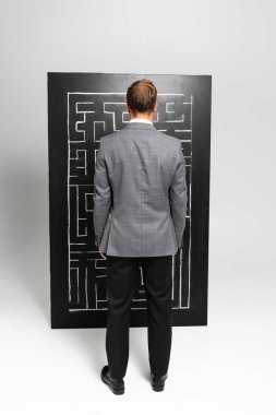 back view of businessman in suit looking at labyrinth  clipart