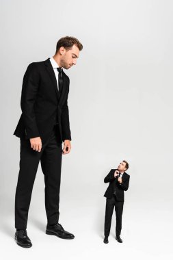 businessman in suit looking at frightened marionette on grey background  clipart