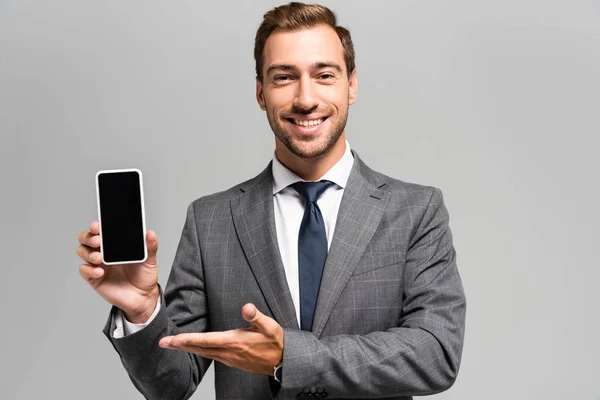 Handsome Smiling Businessman Suit Pointing Hand Smartphone Isolated Grey — Stock Photo, Image