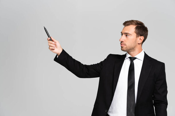 handsome businessman businessman in suit holding marker isolated on grey