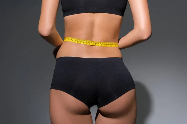 黒い背景に腰に測定テープを保持下着のスリムな女性の部分的なビュー — ストック写真