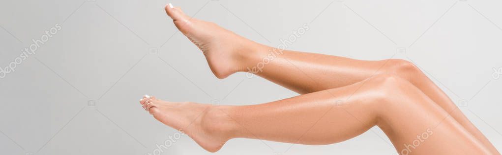 cropped view of beautiful female legs on grey background, panoramic shot