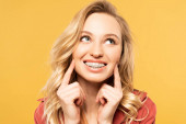 Lächelnde blonde Frau mit Zahnspange blickt vereinzelt auf gelb