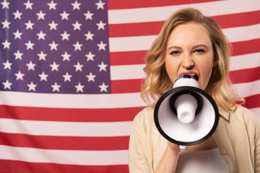 Arkasında Amerikan bayrağı olan hoparlörden bağıran genç bir kadın.