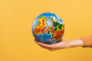 Cropped view of globe in woman hand isolated on yellow clipart
