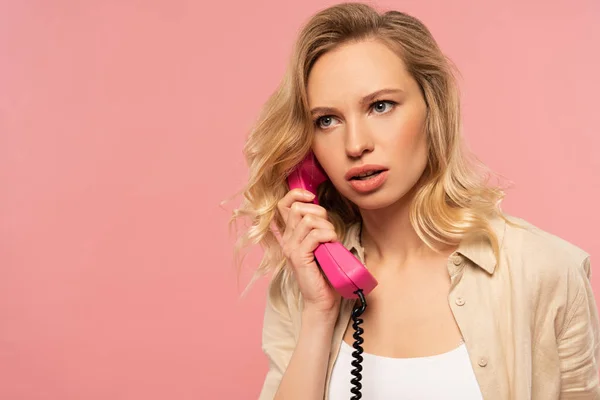 严肃的金发女人在复古电话里用粉红隔离 — 图库照片