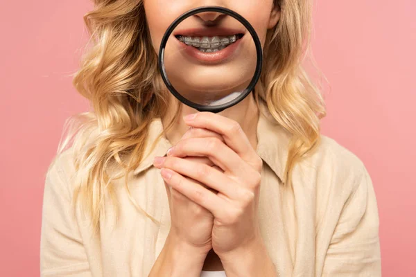 带牙套的妇女手持用粉红隔离的放大镜的剪影 — 图库照片