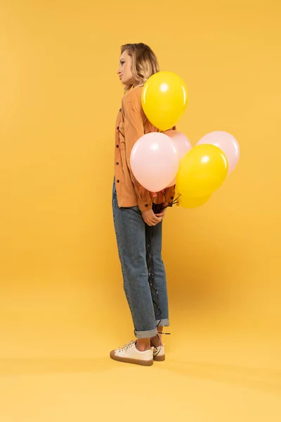 Vista Lateral Una Mujer Rubia Sosteniendo Globos Sobre Fondo Amarillo —  Fotos de Stock