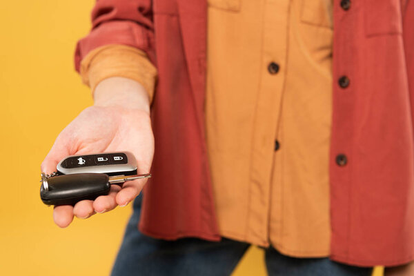 Обрезанный вид женщины, держащей ключи от машины изолированы на желтый
