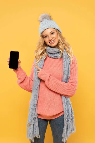 Smiling Woman Hat Scarf Pointing Smartphone Blank Screen Isolated Yellow — Stock Photo, Image