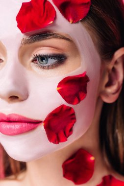Gül yapraklı, maske takmış güzel bir kadının yakın görüntüsü.