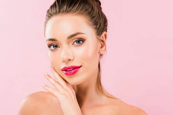 naked beautiful woman with pink lips posing with hand near face isolated on pink 