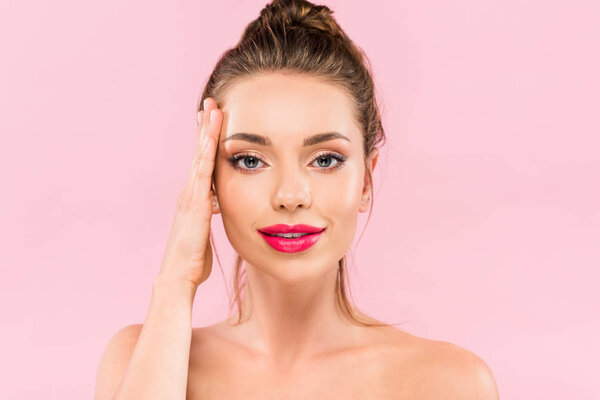 naked beautiful woman with pink lips posing with hand on face isolated on pink 